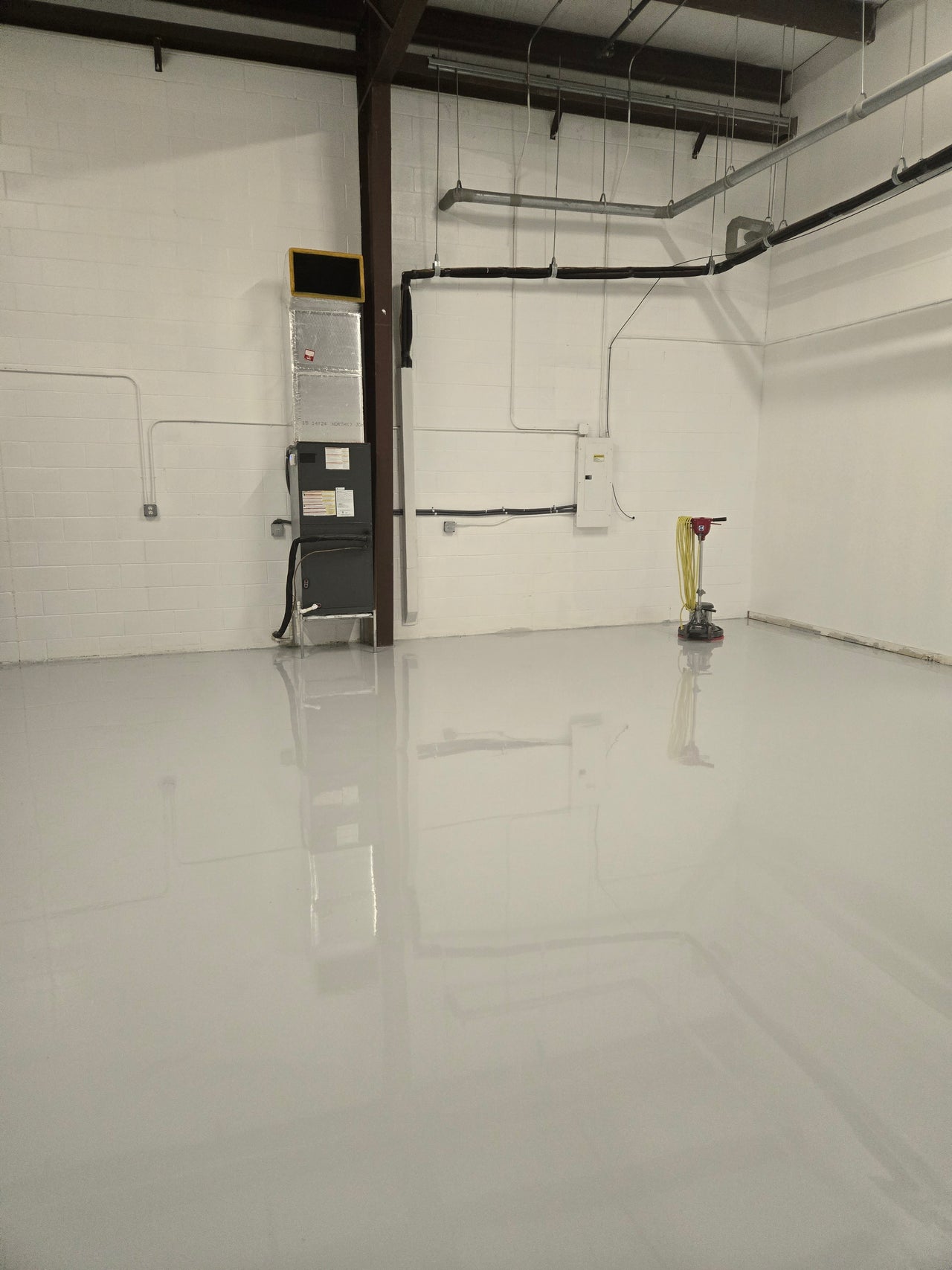 High-gloss light gray 100% solids industrial epoxy floor coating in a large commercial warehouse