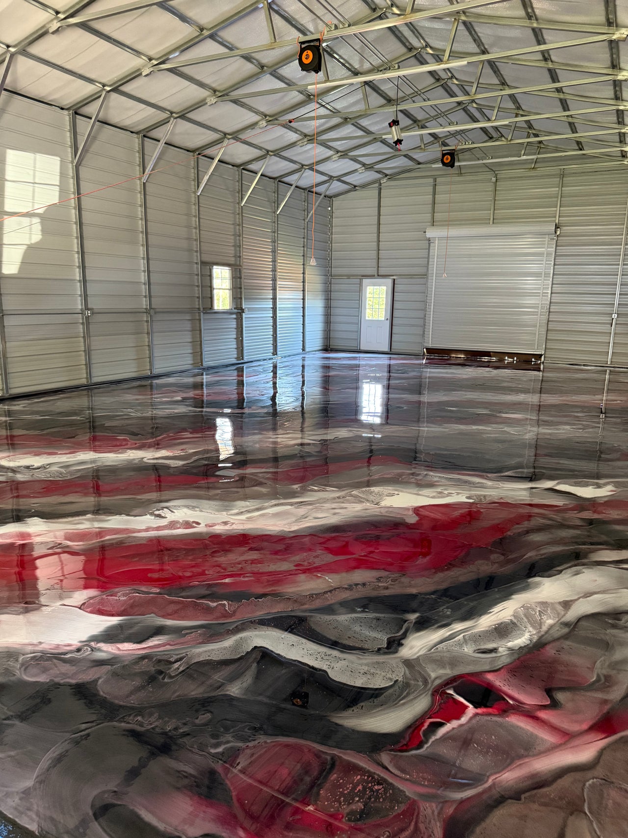 Large warehouse featuring a high-gloss black, red, and white metallic epoxy floor system using Labsurface LABPOX LV UV