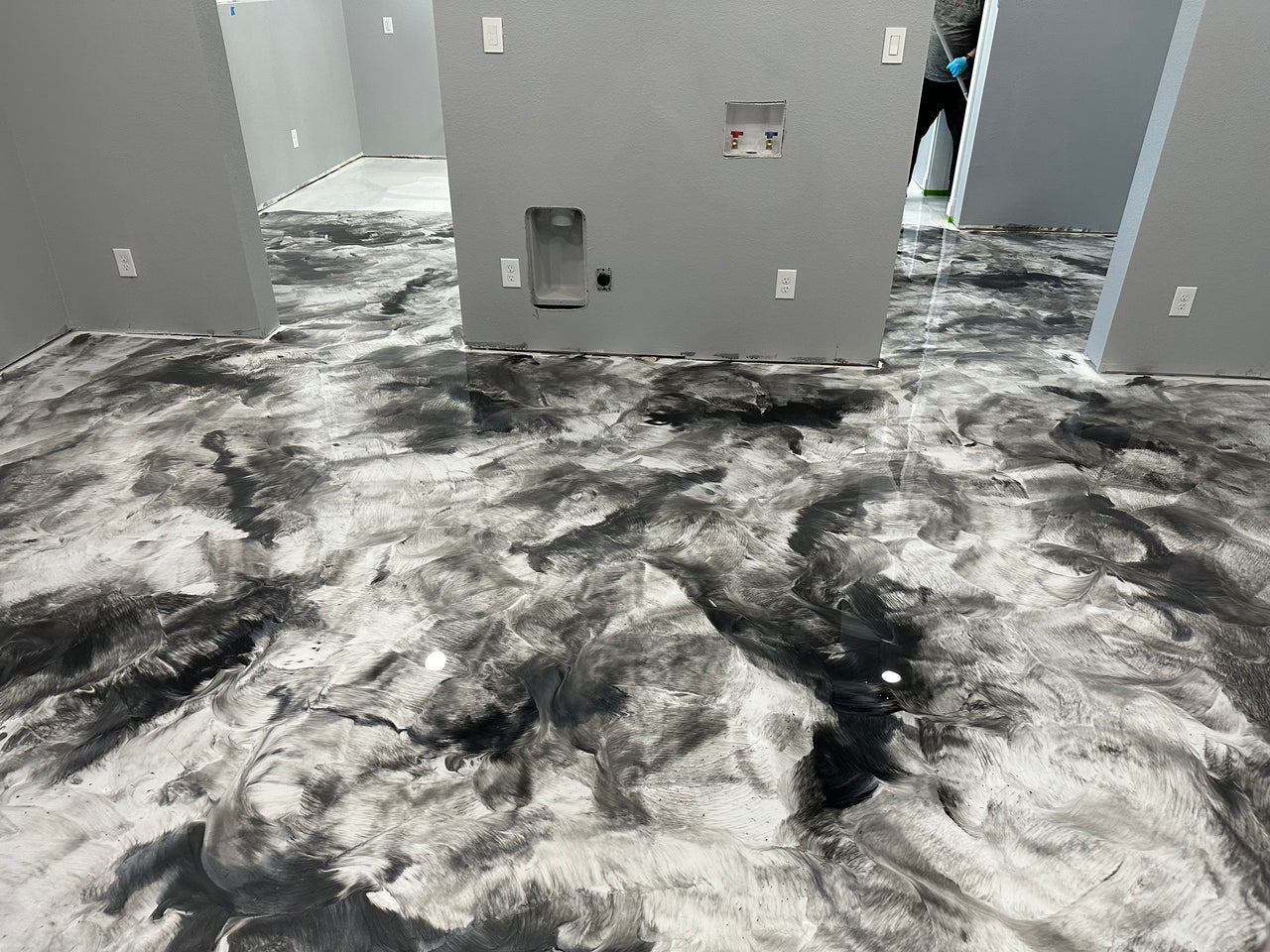 Custom marbled metallic epoxy floor in a modern room, featuring a high-gloss blend of Bright White, Satin Gray, and Black Pearl pigments.