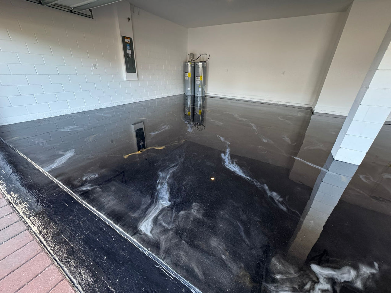 metallic garage floor installation with gold and white veining over a deep black base, providing a reflective and durable surface.