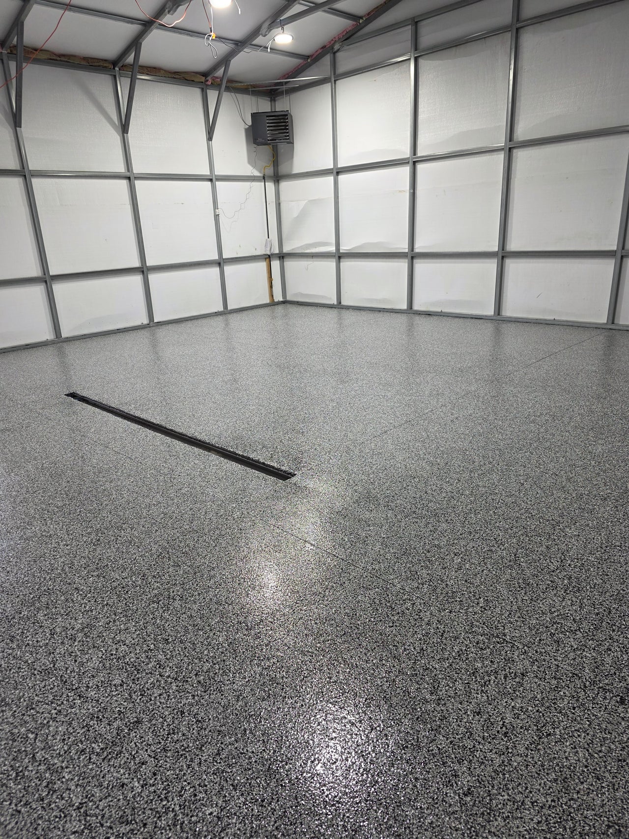 Full broadcast domino flake garage floor coating with a high-gloss polyaspartic topcoat for a durable granite-look finish.