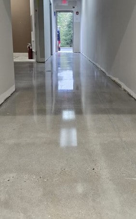A long commercial hallway featuring polished concrete with a mirror-like high gloss finish achieved using the Premera One Day Polish system with Crystal Guard.