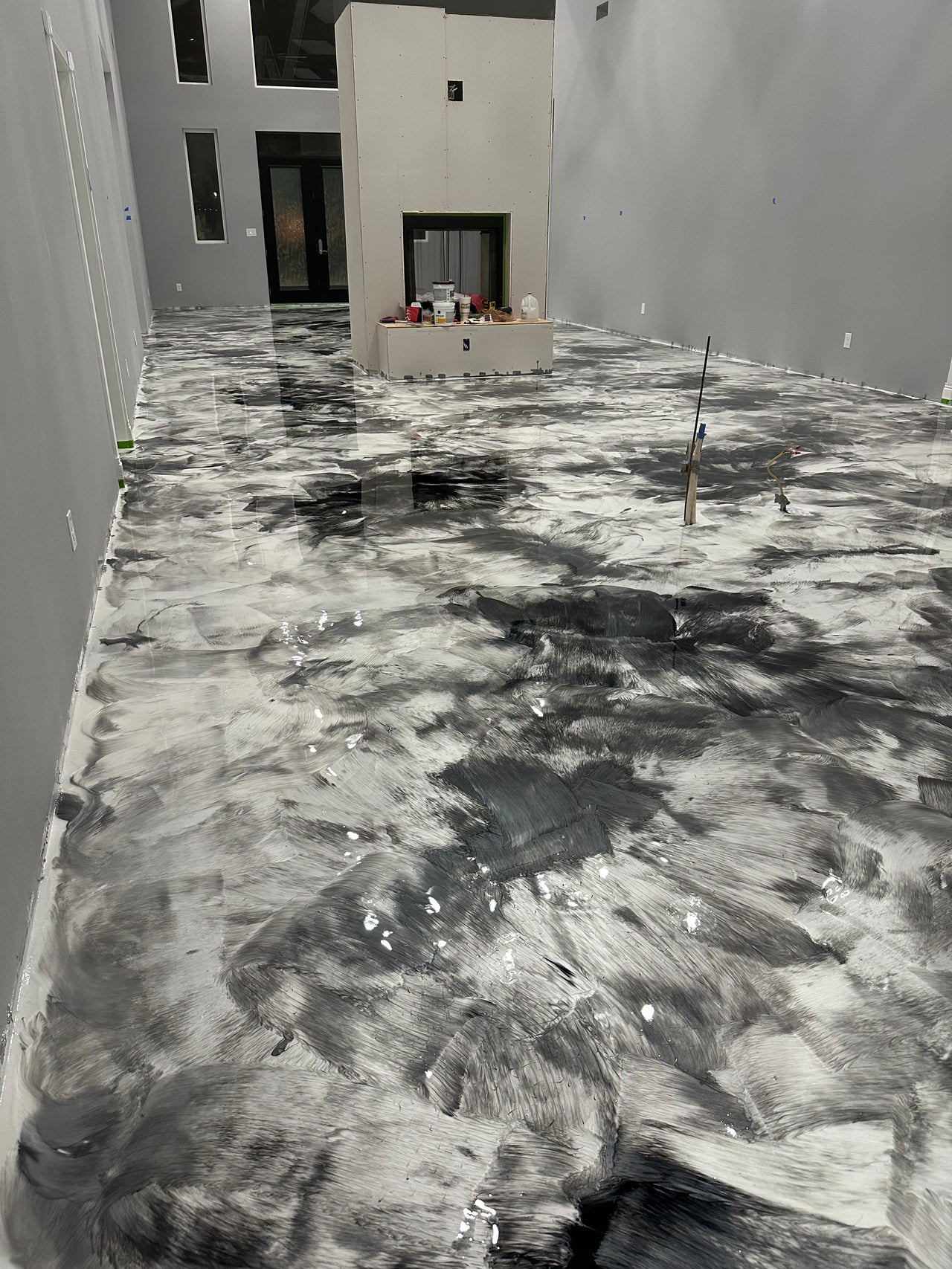 Modern residential hallway featuring a high-gloss white and charcoal metallic epoxy floor with a marble-swirl finish