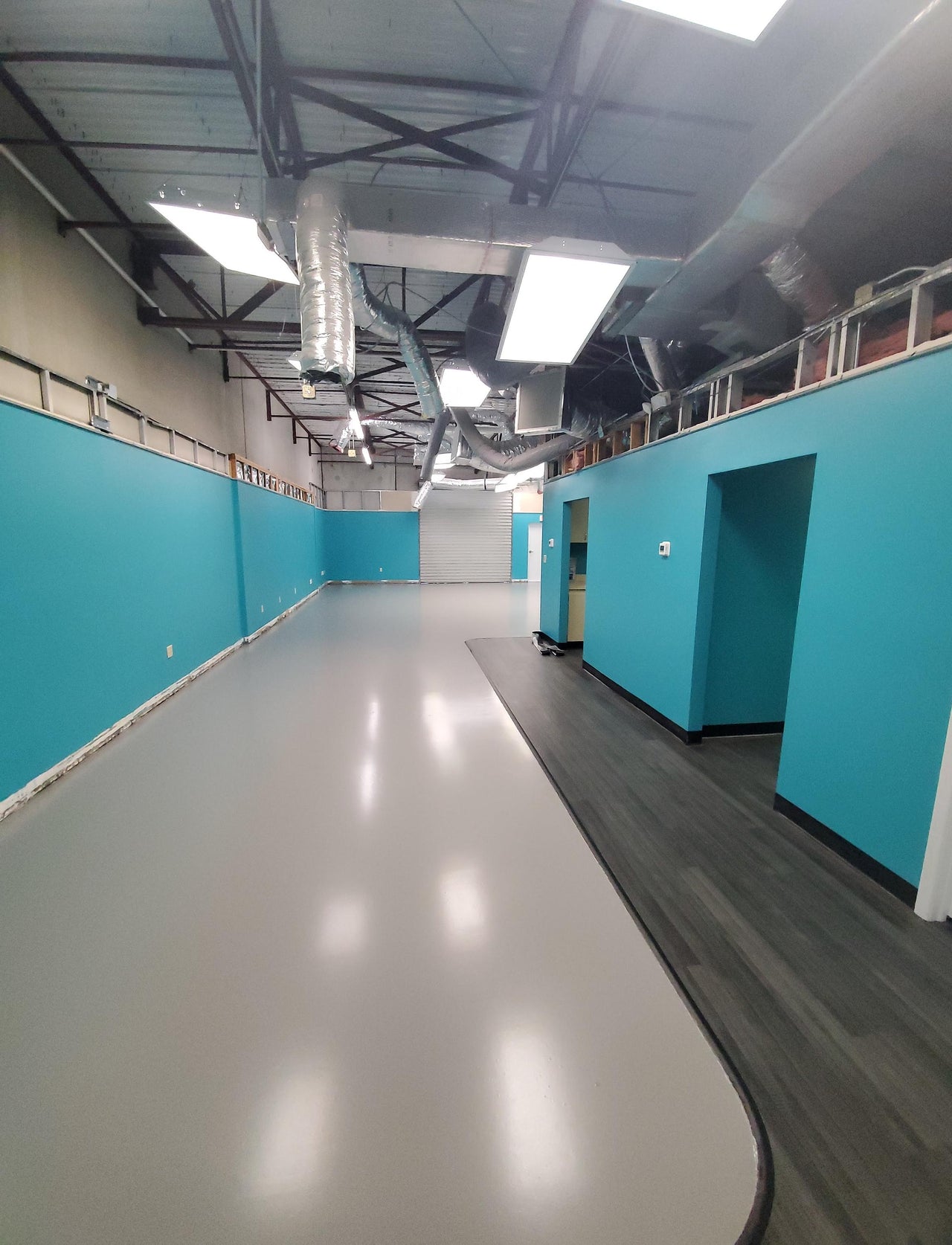 Professional application of Lite Gray self leveling industrial grade epoxy on a large commercial floor, providing chemical and abrasion resistance.