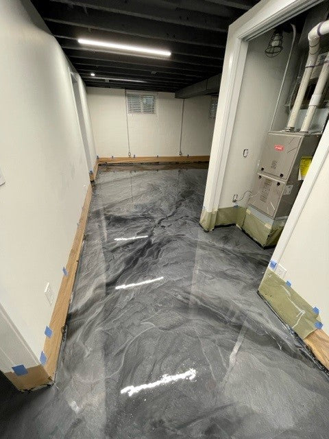 Metallic Dream silver and black metallic epoxy floor installation in a basement, featuring high-gloss reflective marble patterns and 100% solids resin.