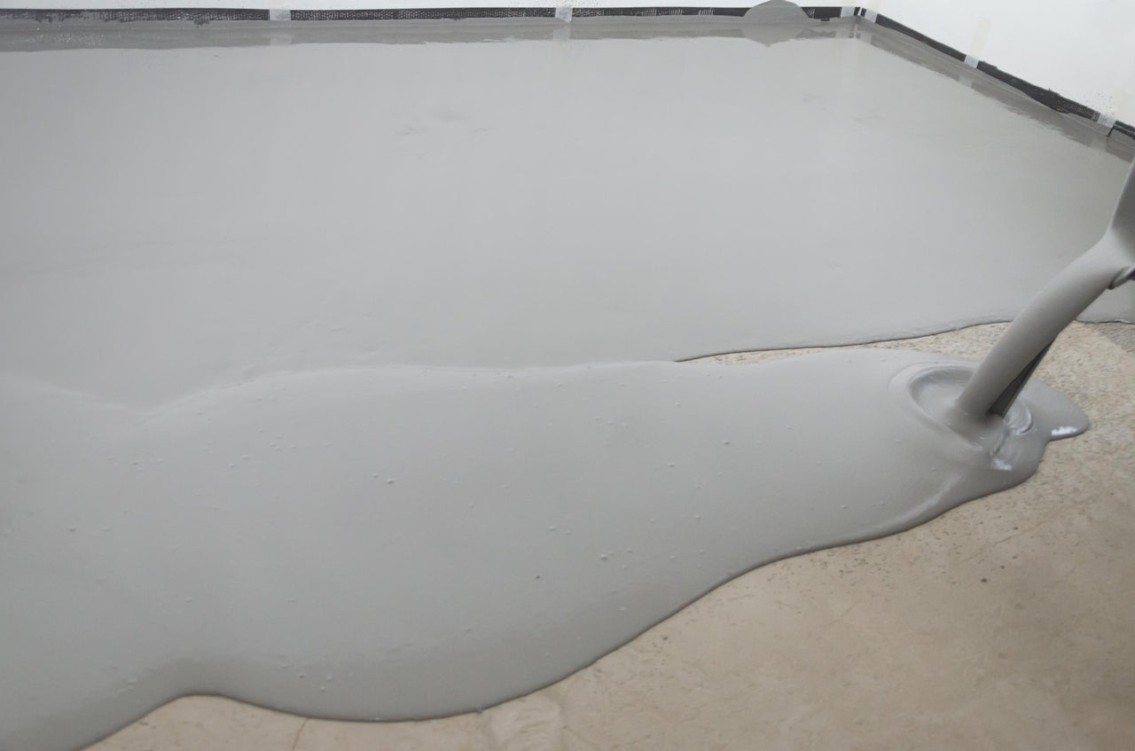 Continuous pour of Lite Gray 100% solids self leveling epoxy resin, showing the excellent flow and leveling properties of the industrial system.